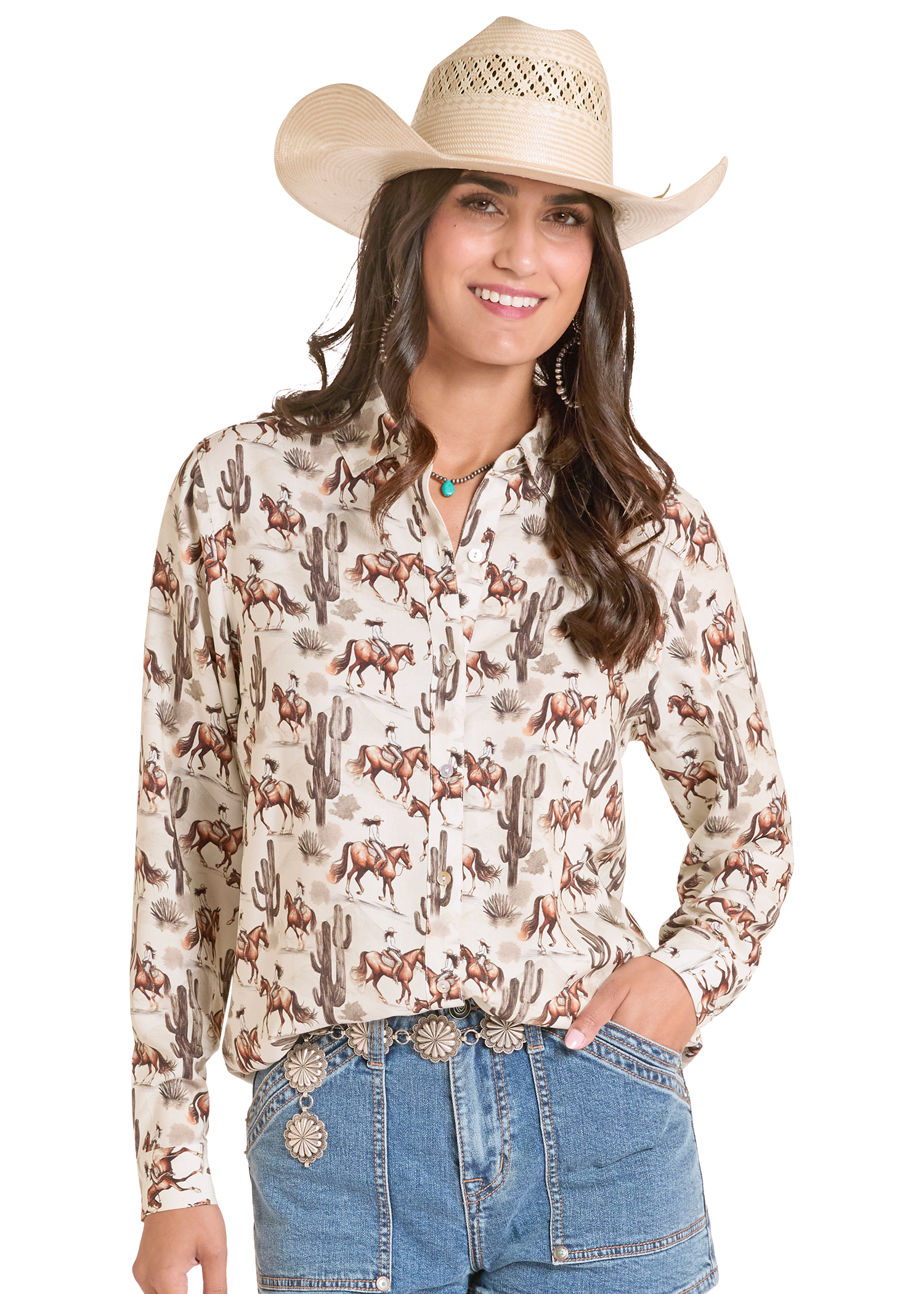 Woman wearing a long-sleeve Western-style shirt with horse and cactus pattern, paired with a cowboy hat and jeans on a white background.