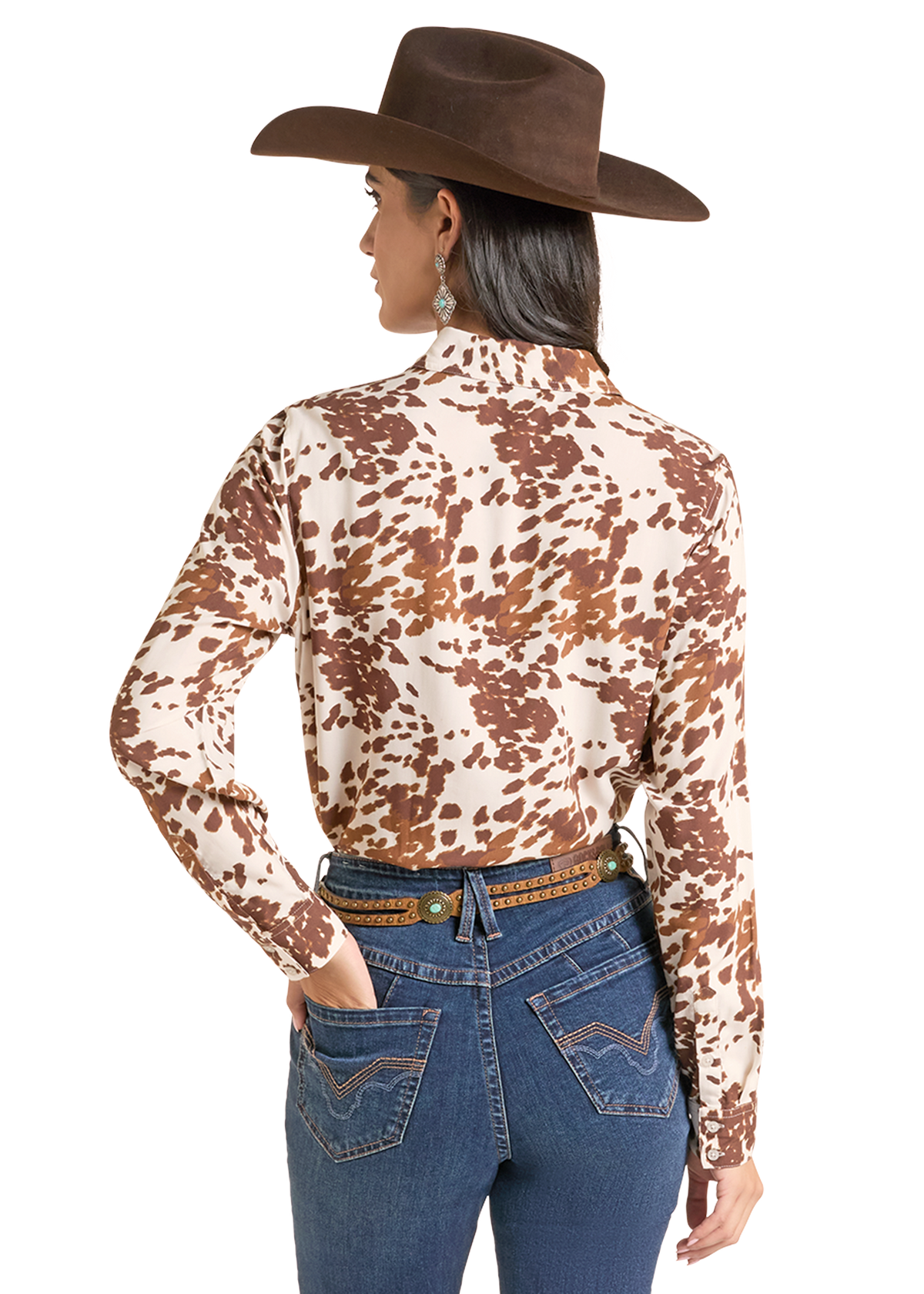 A woman shown from the back wearing a brown and beige cow-print long-sleeve western shirt, a brown cowboy hat, and blue jeans against a plain white background.