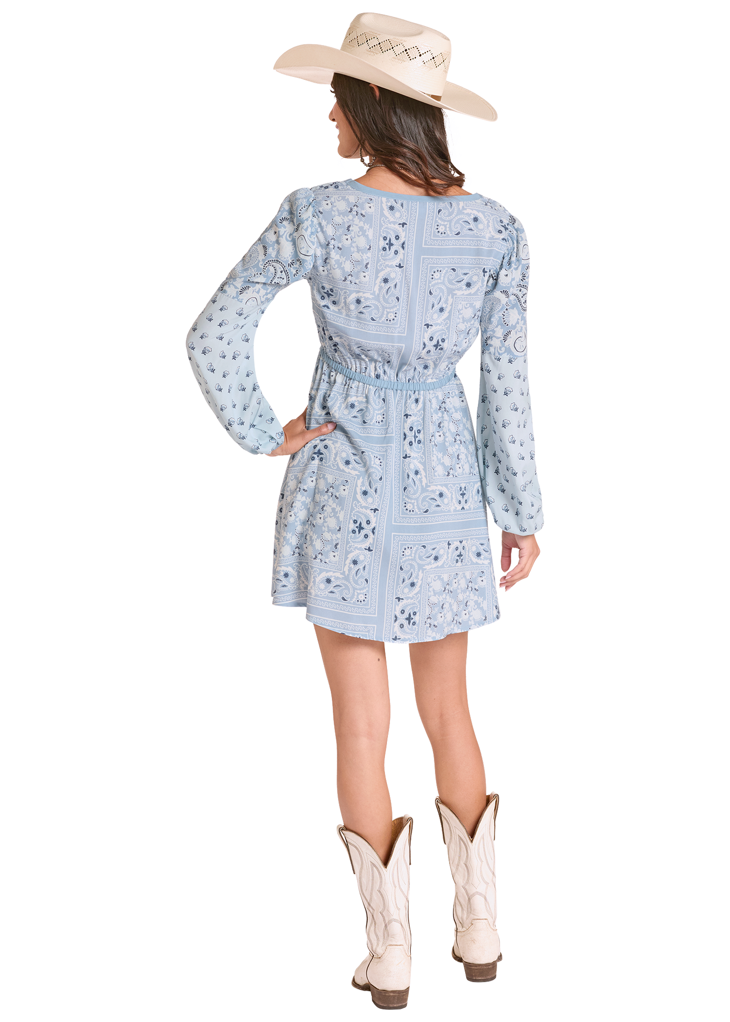 Woman wearing a light blue floral dress with long sleeves, white cowboy boots, and a beige cowboy hat on a white background.