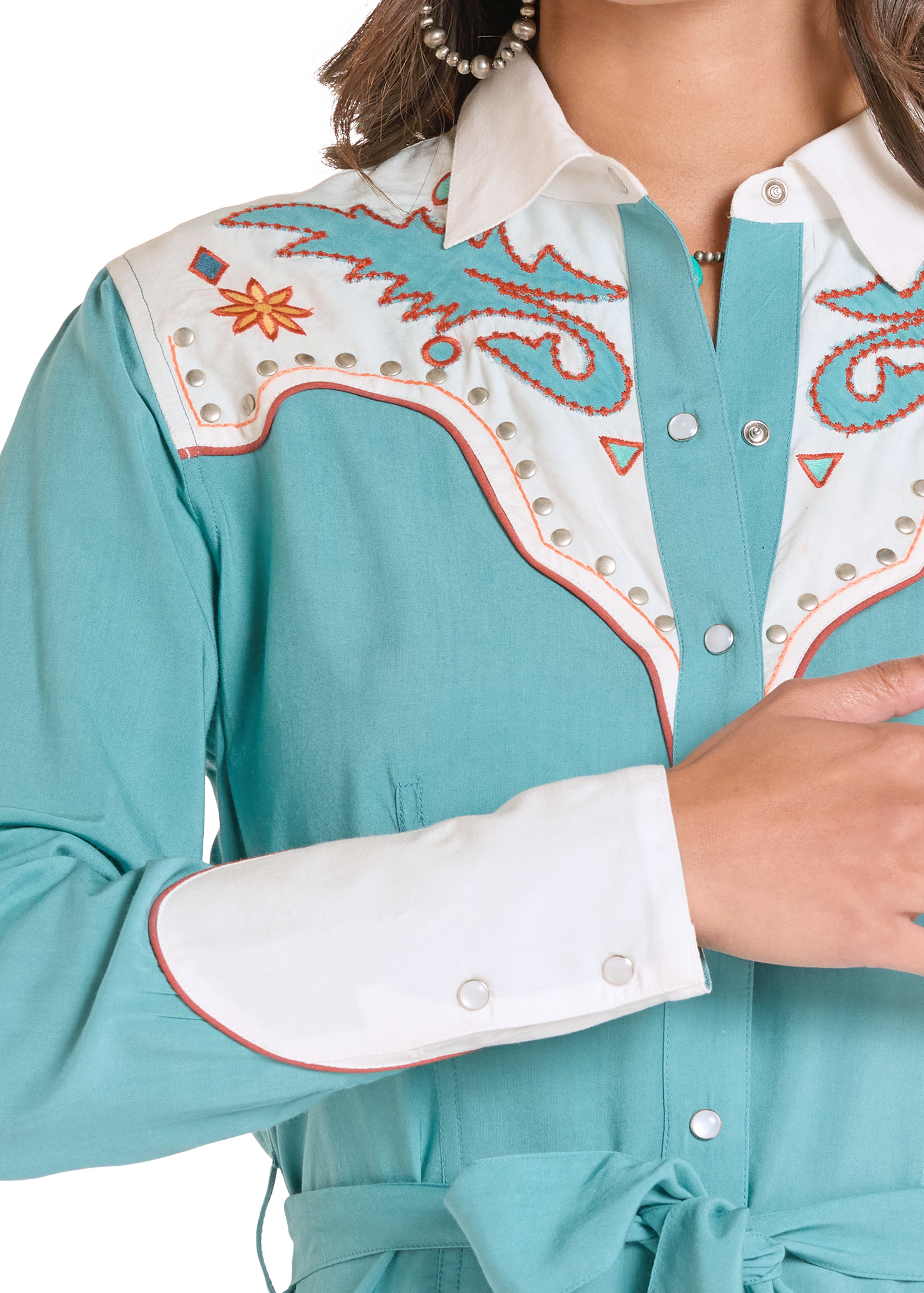 Close-up of a turquoise blouse with white and orange embroidery