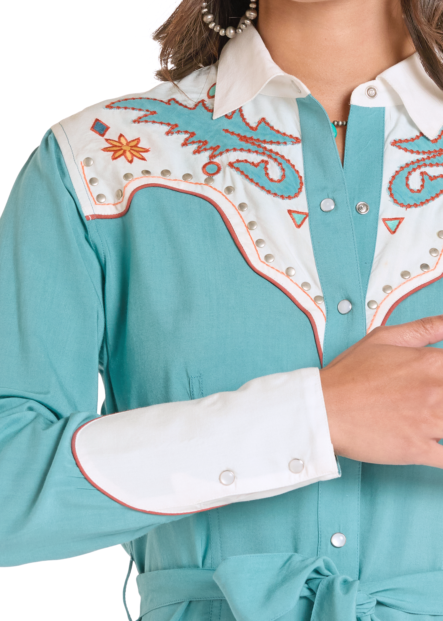Close-up of a turquoise blouse with white and orange embroidery