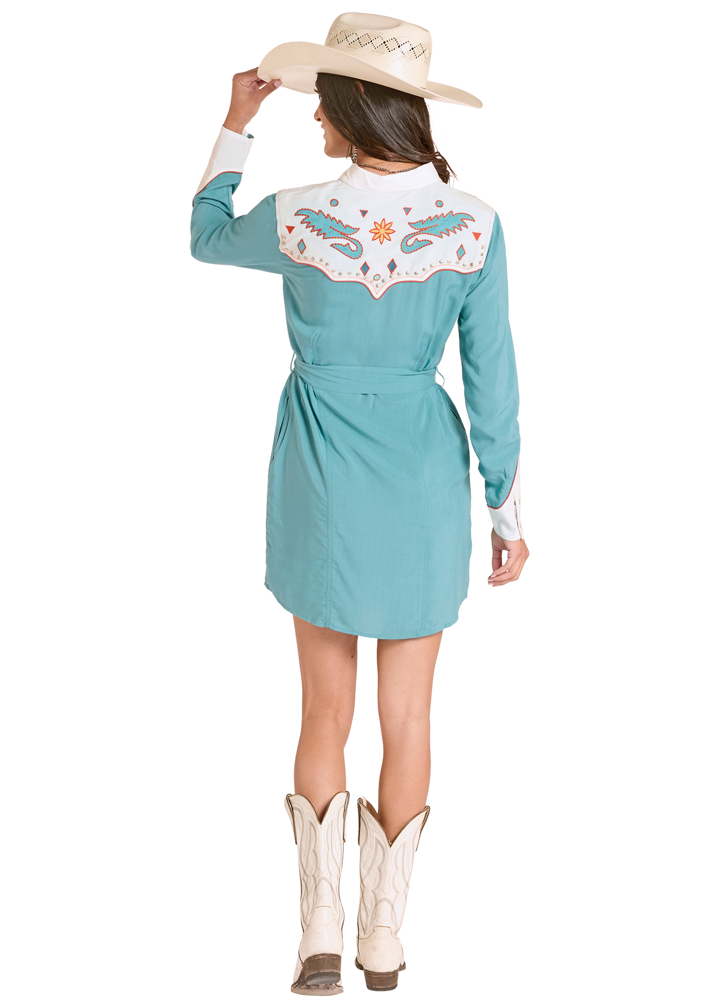 Woman wearing a turquoise western-style dress with floral embroidery, white boots, and a beige hat on a white background.