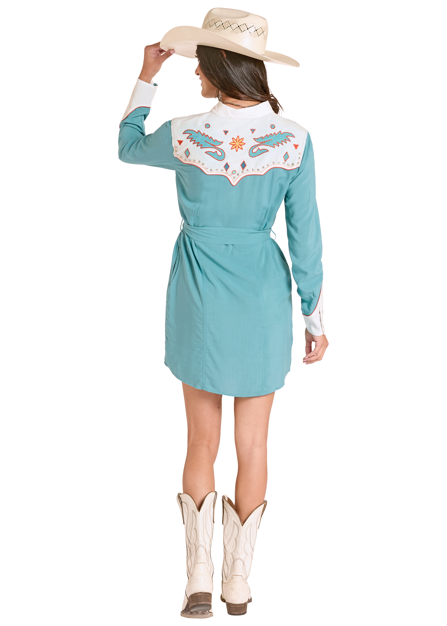 Woman wearing a turquoise western-style dress with floral embroidery, white boots, and a beige hat on a white background.