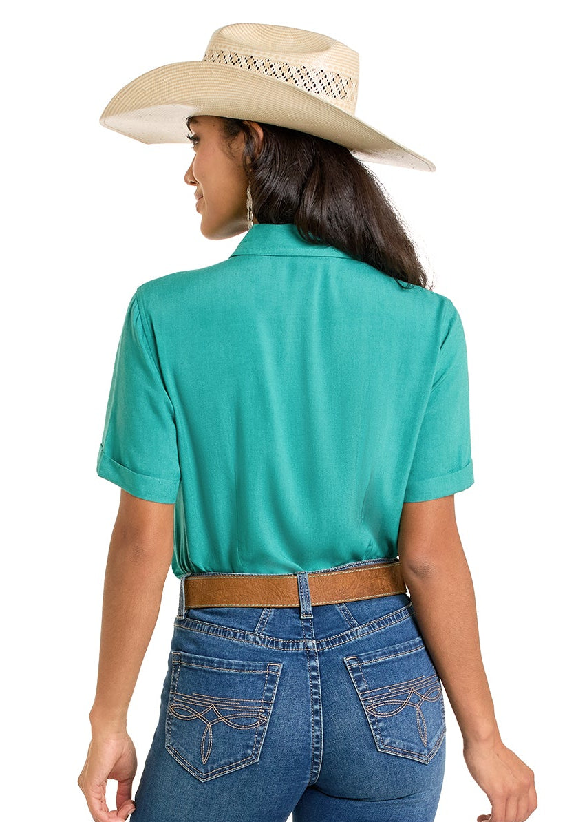 Woman wearing a turquoise shirt and blue jeans with a beige hat on a white background