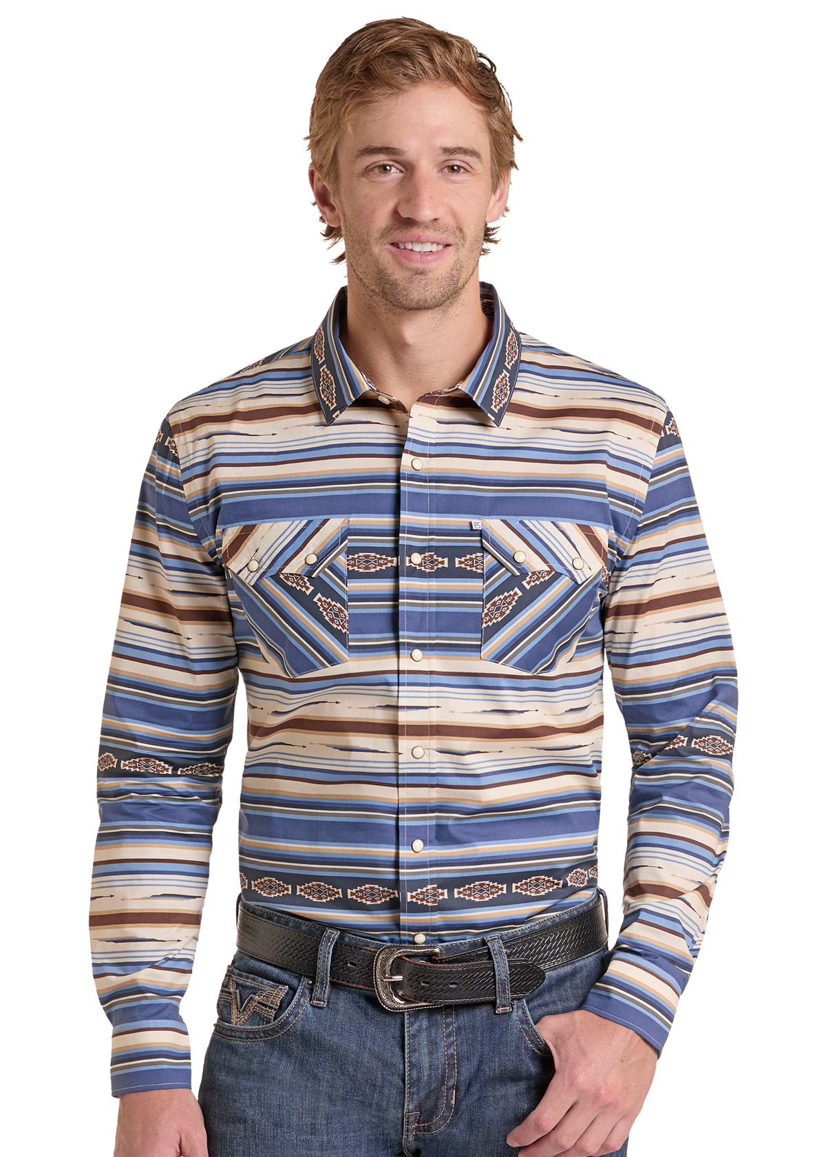 A man wearing a long-sleeve western-style button-up shirt with blue, beige, and brown striped patterns and geometric designs on the chest, paired with blue jeans and a black belt.