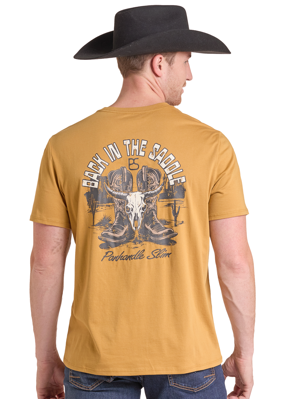 A man wearing a black cowboy hat and a mustard yellow t-shirt, viewed from the back. The t-shirt features a large graphic print on the back with a cowboy skull, boots, and the text 'BACK IN THE SADDLE' and 'Panhandle Slim'.