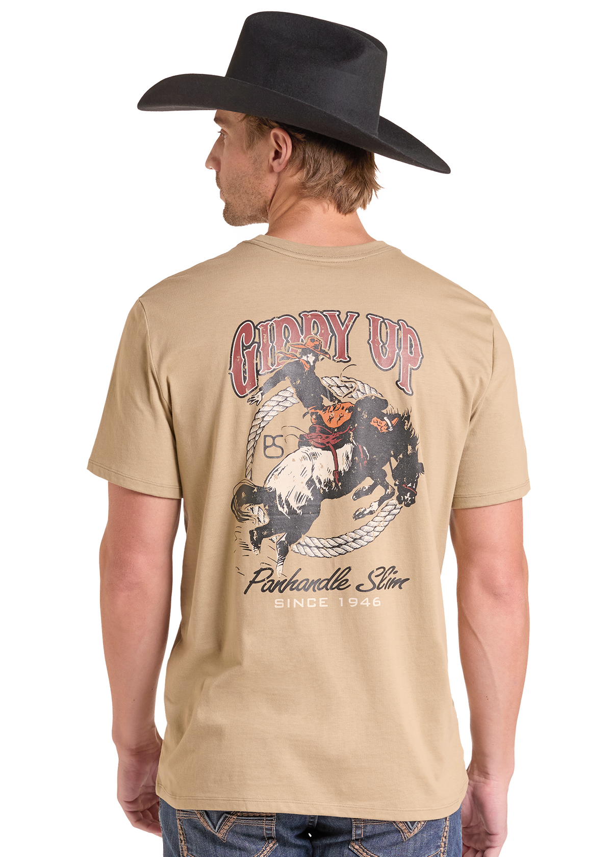 A man wearing a beige graphic t-shirt and a black cowboy hat, shown from the back. The t-shirt features a large western-themed graphic with the text 'GIDDY UP'.