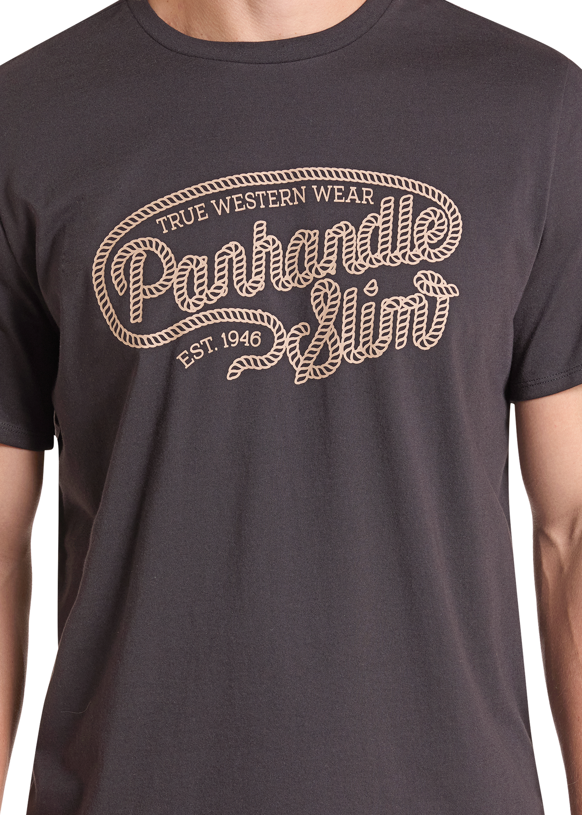A close-up of a person wearing a dark charcoal gray t-shirt with a beige graphic print that reads 'True Western Wear Panhandle Slim Est. 1946'.