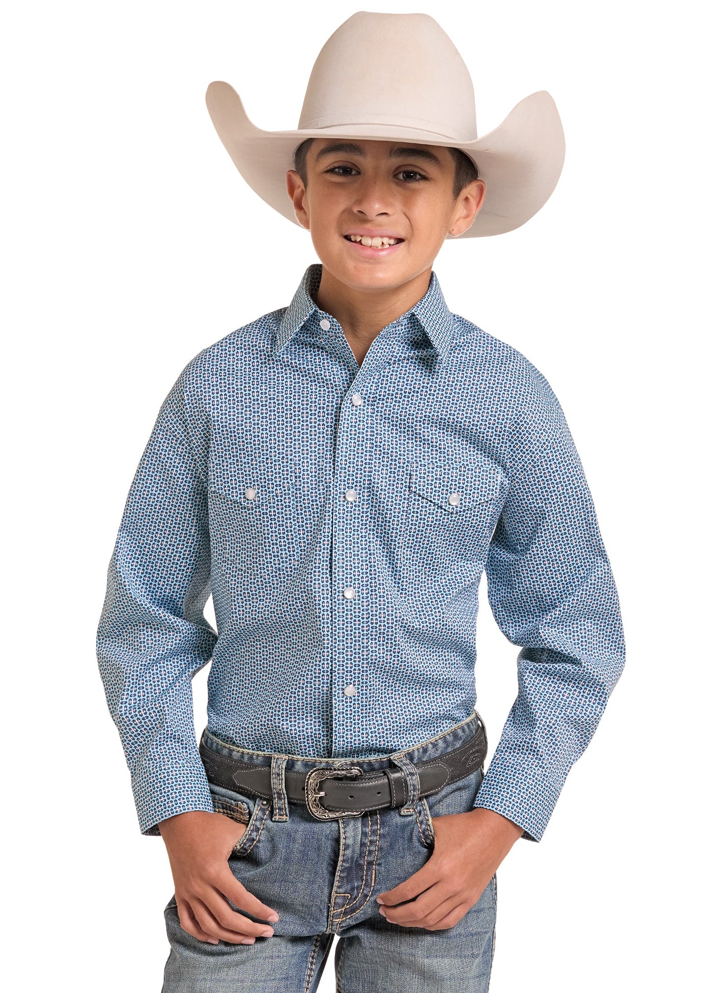 A young boy wearing a light blue patterned western long-sleeve shirt, blue jeans, and a cream-colored cowboy hat, standing against a solid white background.