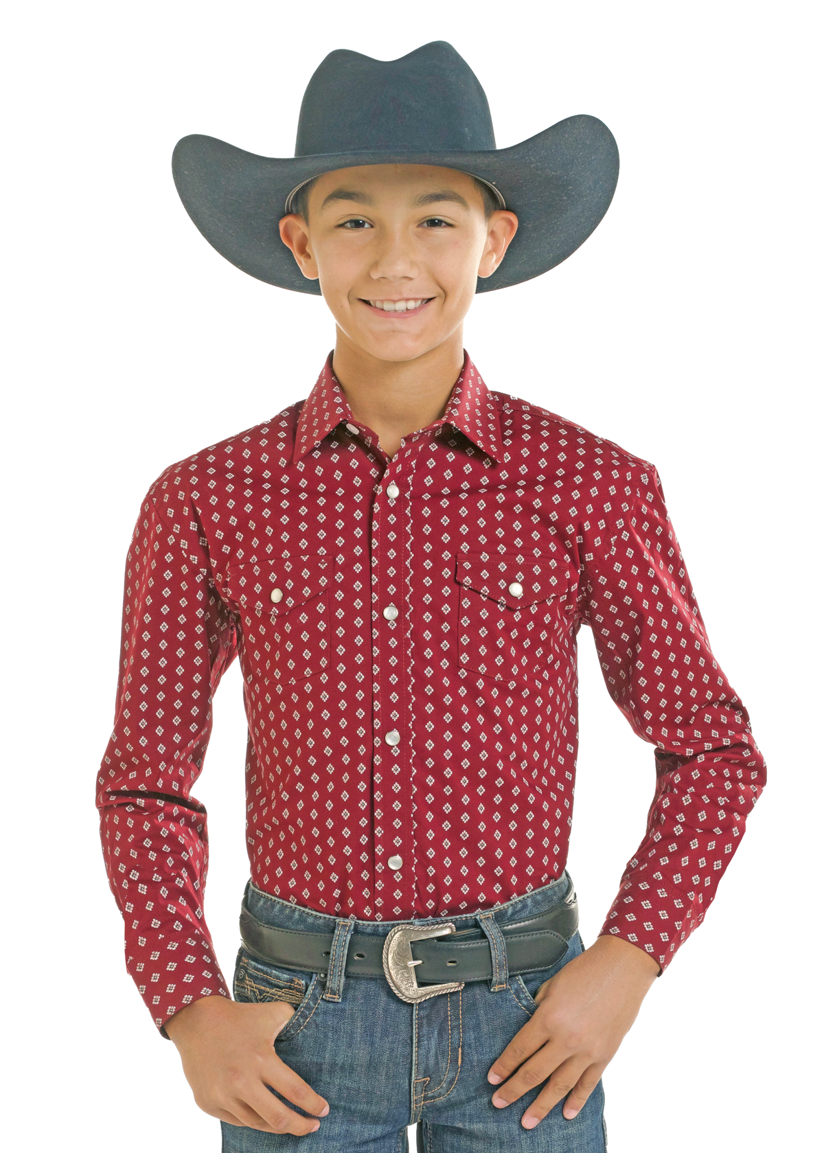 A young boy modeling a red long-sleeve western shirt with a white geometric pattern, paired with a dark gray cowboy hat, blue jeans, and a silver belt.