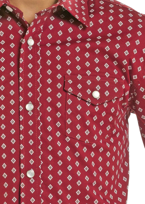 Details of a boys red long-sleeve western shirt with a white geometric pattern and snap chest pocket.
