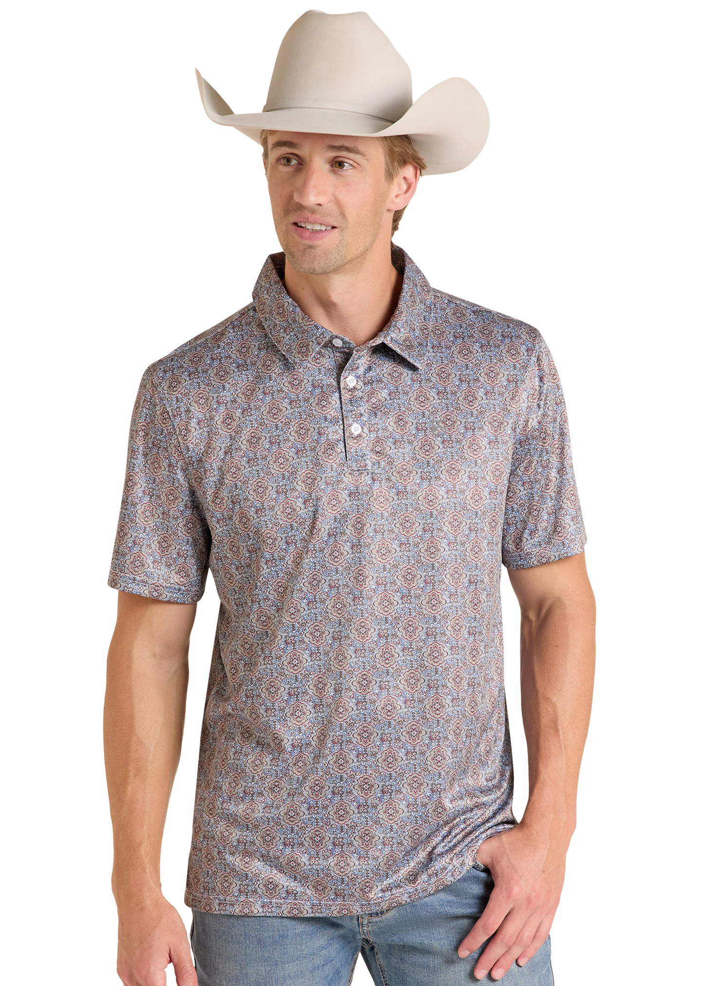 A man wearing a short-sleeve polo shirt with a dense blue, red, and beige paisley pattern, paired with a light beige cowboy hat and blue jeans, set against a plain white background.