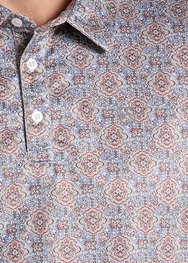 closeup of a polo shirt with a dense blue, red, and beige paisley pattern.