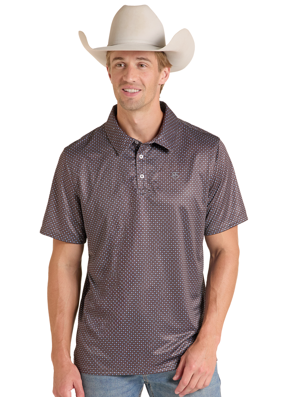 A man wearing a brown short-sleeve polo shirt with a small white geometric pattern, paired with a beige cowboy hat and blue jeans, against a plain white background.