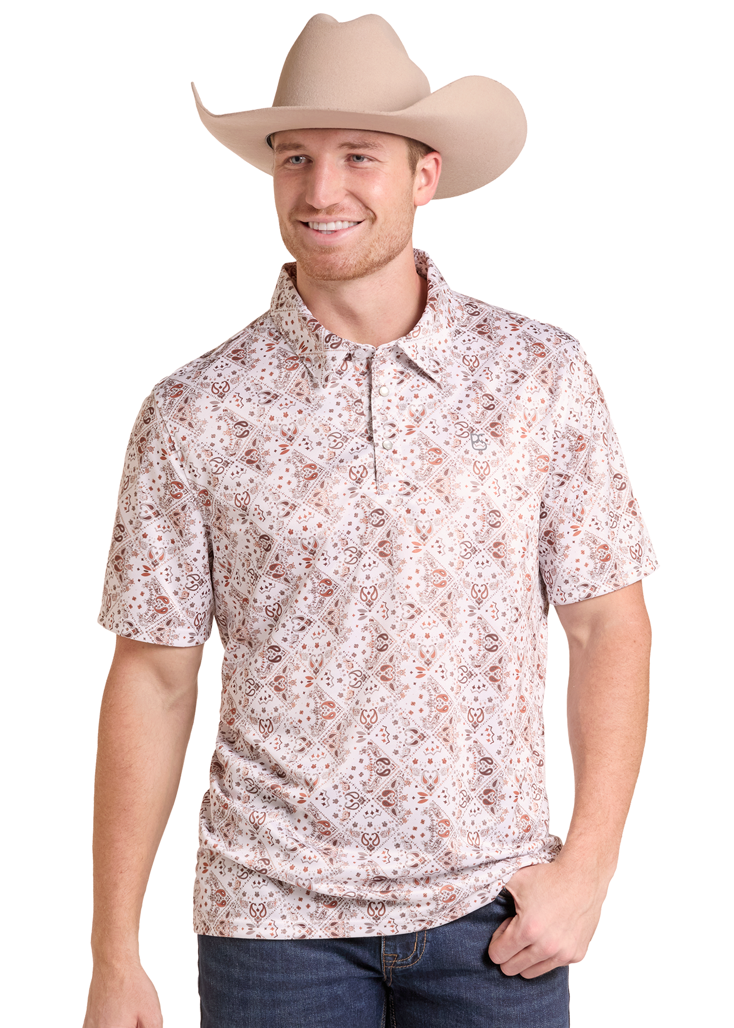 A man wearing a beige cowboy hat and a short-sleeve collared button-up shirt with a small brown and black paisley pattern on a light beige background, paired with dark blue jeans, against a solid white background.