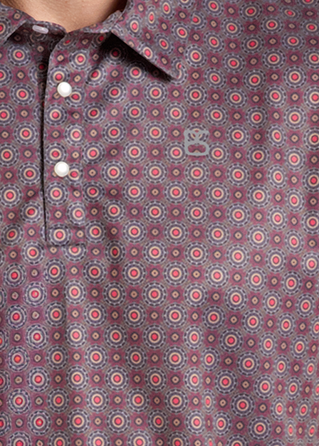 A close up of a short-sleeve button-up polo shirt with a small geometric pattern in muted red, blue, and brown tones. 