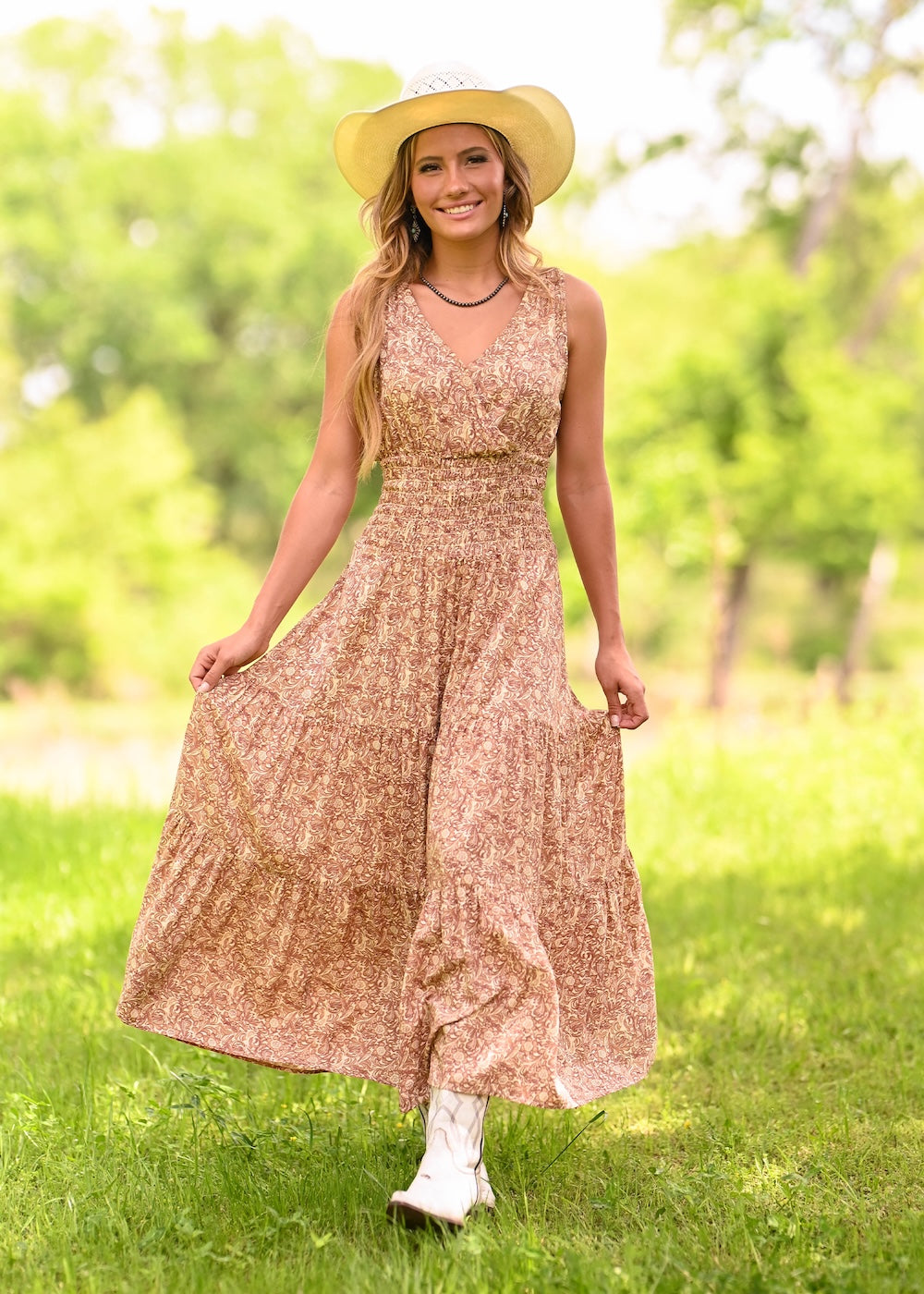 A woman wearing a sleeveless, tiered maxi dress with a beige and brown floral pattern.