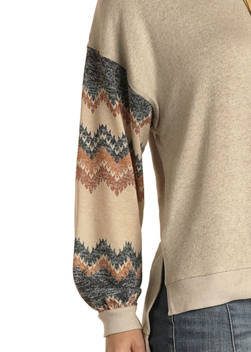 Woman wearing a beige sweater with patterned sleeves on a white background