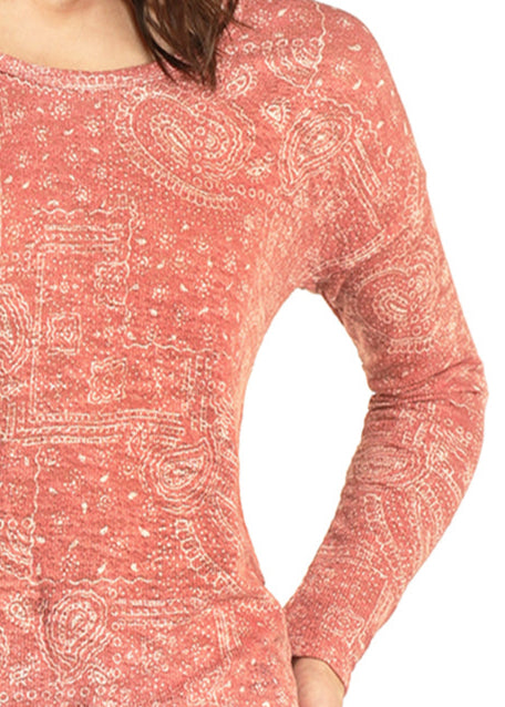 Woman wearing a pink patterned long-sleeve top and jeans on a white background