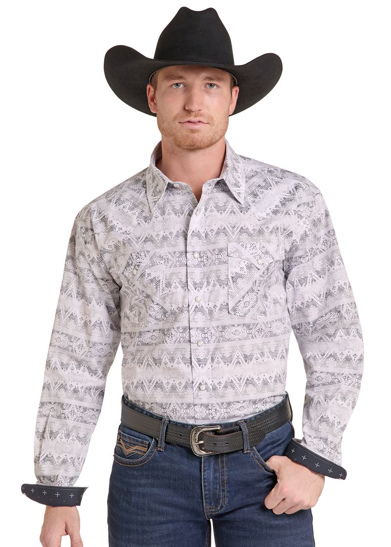 A man wearing a long-sleeve western shirt with a gray and white geometric pattern, paired with a black cowboy hat, dark jeans.