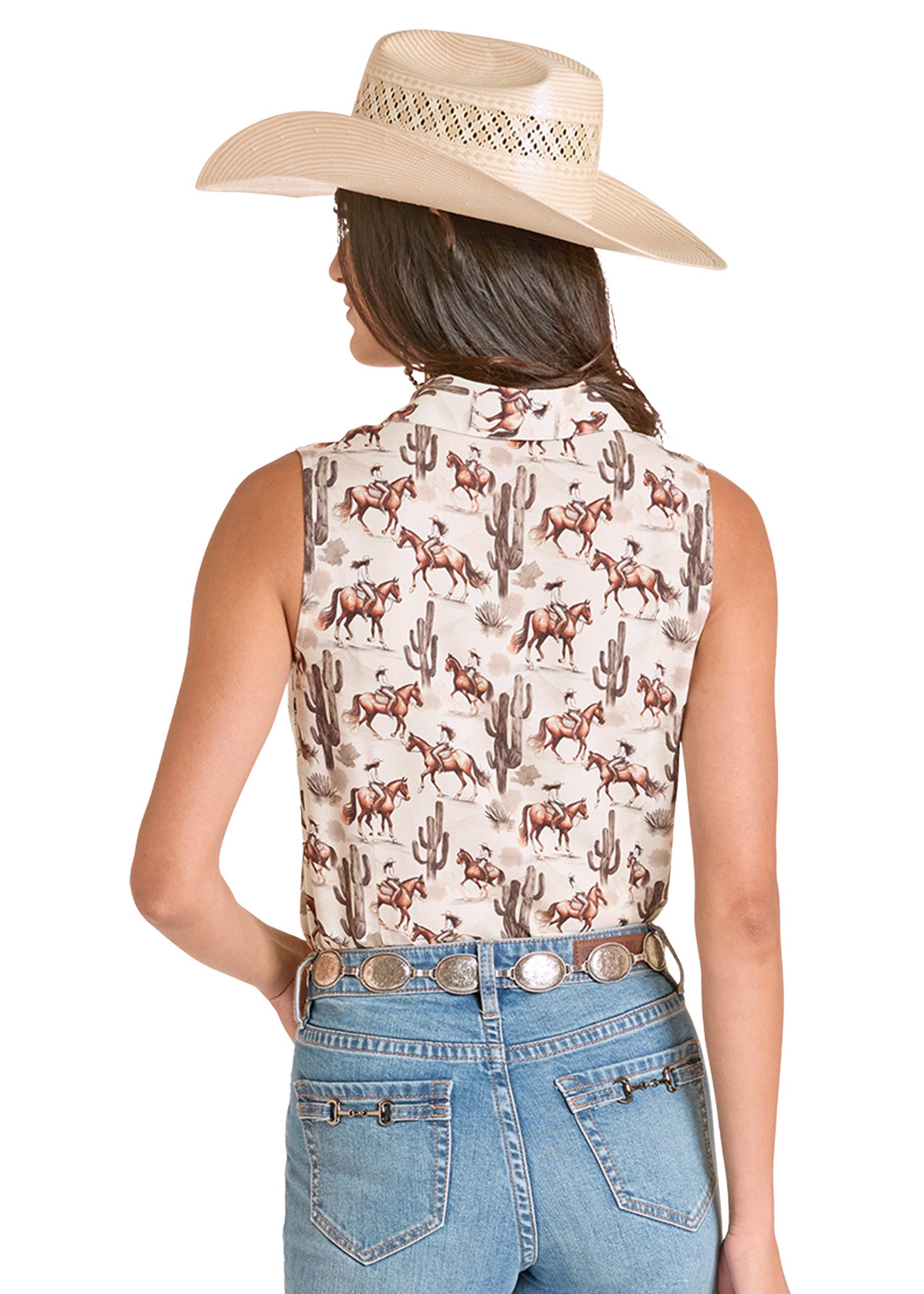 Woman wearing a sleeveless patterned top with horses and cacti, paired with a cowboy hat and jeans on a white background.