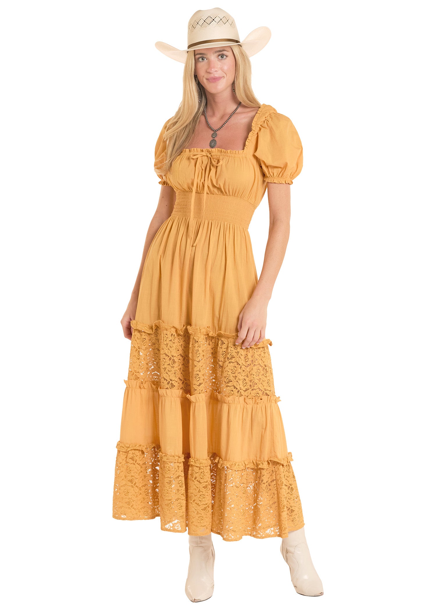 Woman wearing a yellow dress with lace details and a cowboy hat on a white background