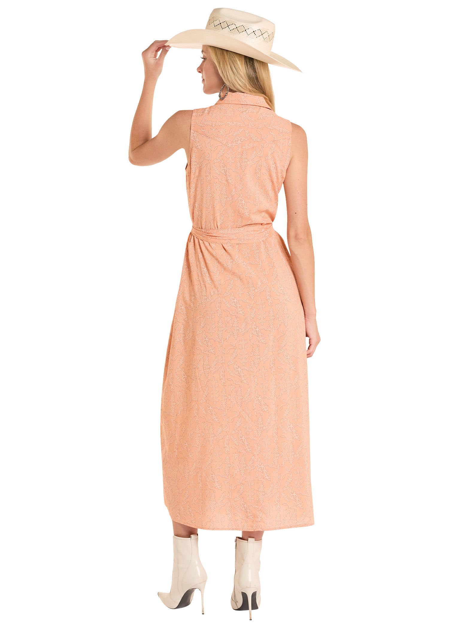 Woman wearing a peach dress and beige hat on a white background