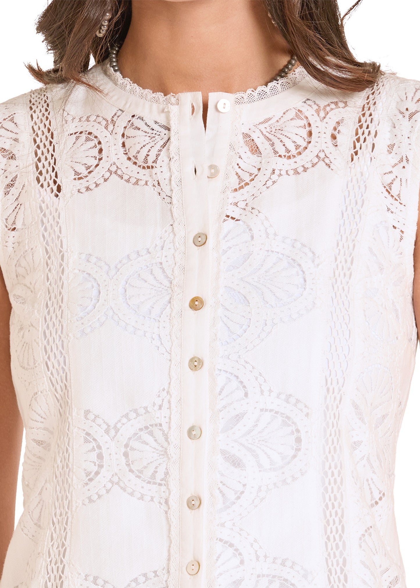 White lace top with button details on a blurred background