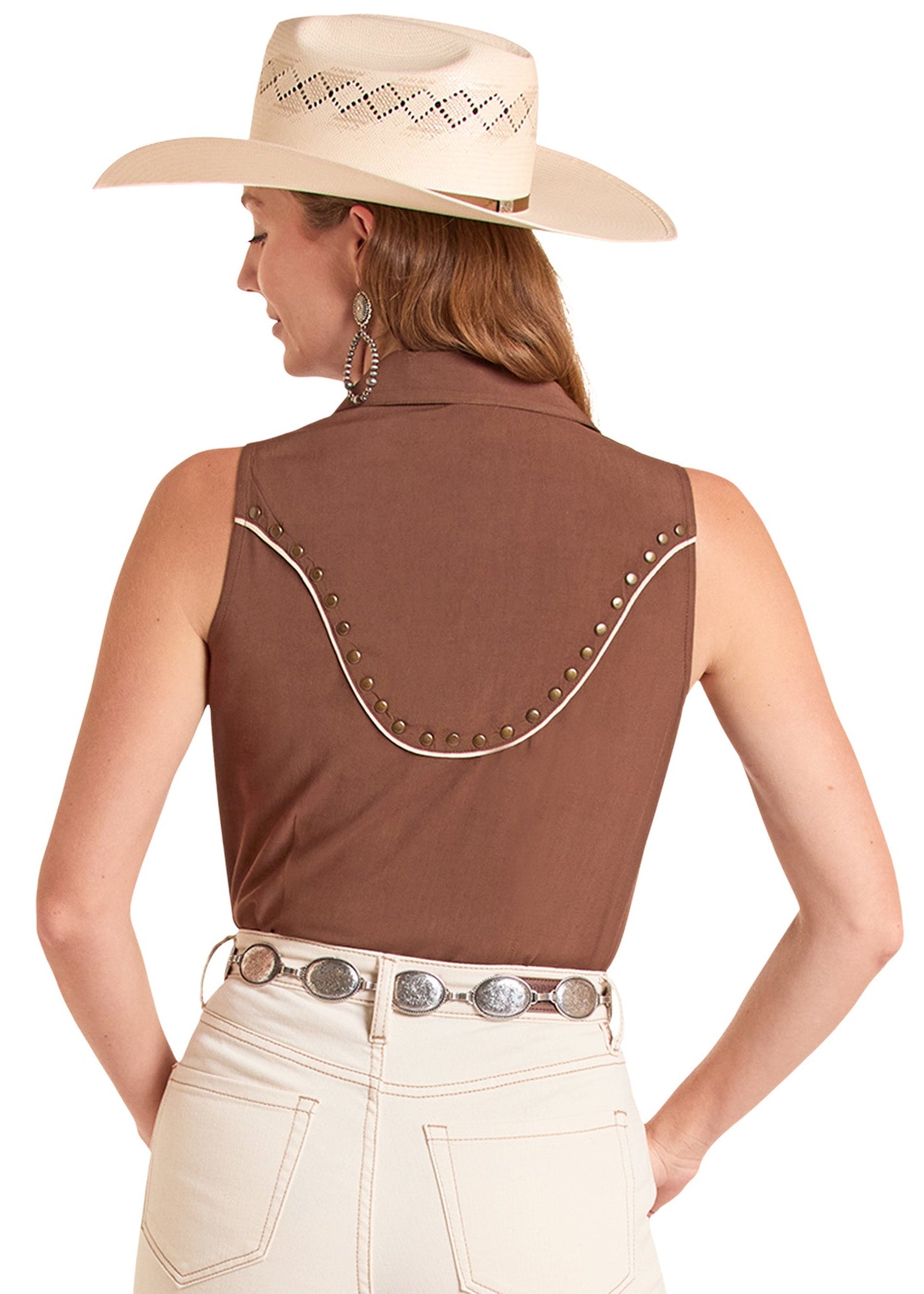 Woman wearing a brown sleeveless top with white stitching and beige pants on a white background