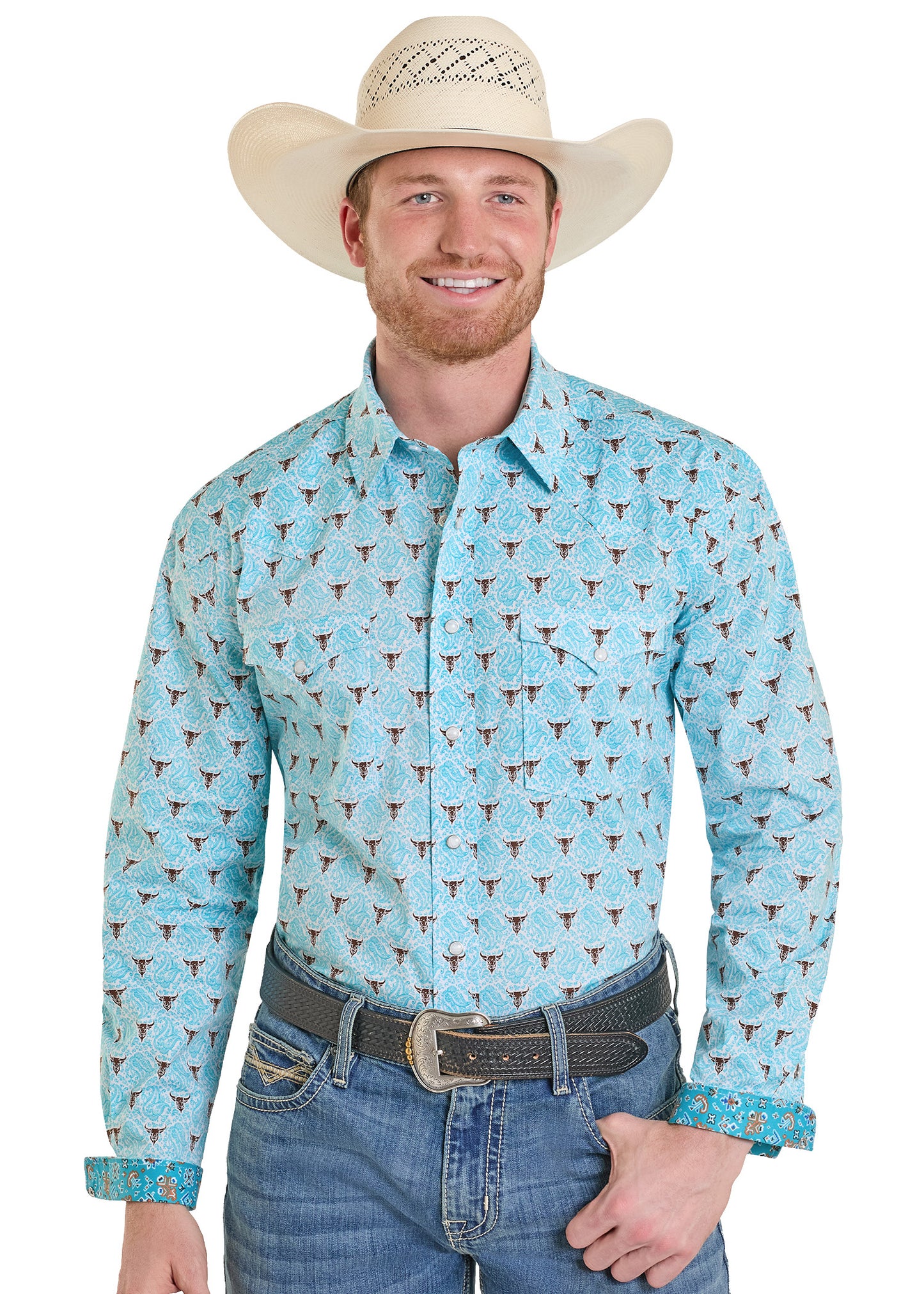 Man wearing a light blue patterned shirt with rolled-up sleeves, blue jeans, and a beige cowboy hat on a white background.