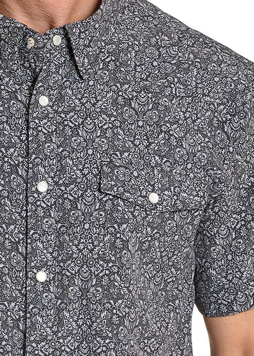 Man wearing a patterned short-sleeve shirt and cowboy hat on a white background