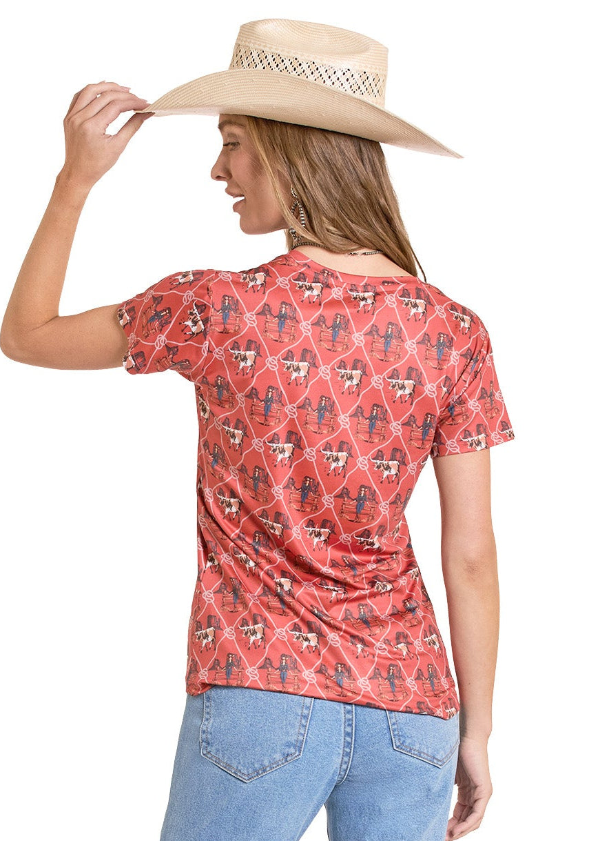 Woman wearing a red patterned shirt and light blue jeans, holding a beige hat.