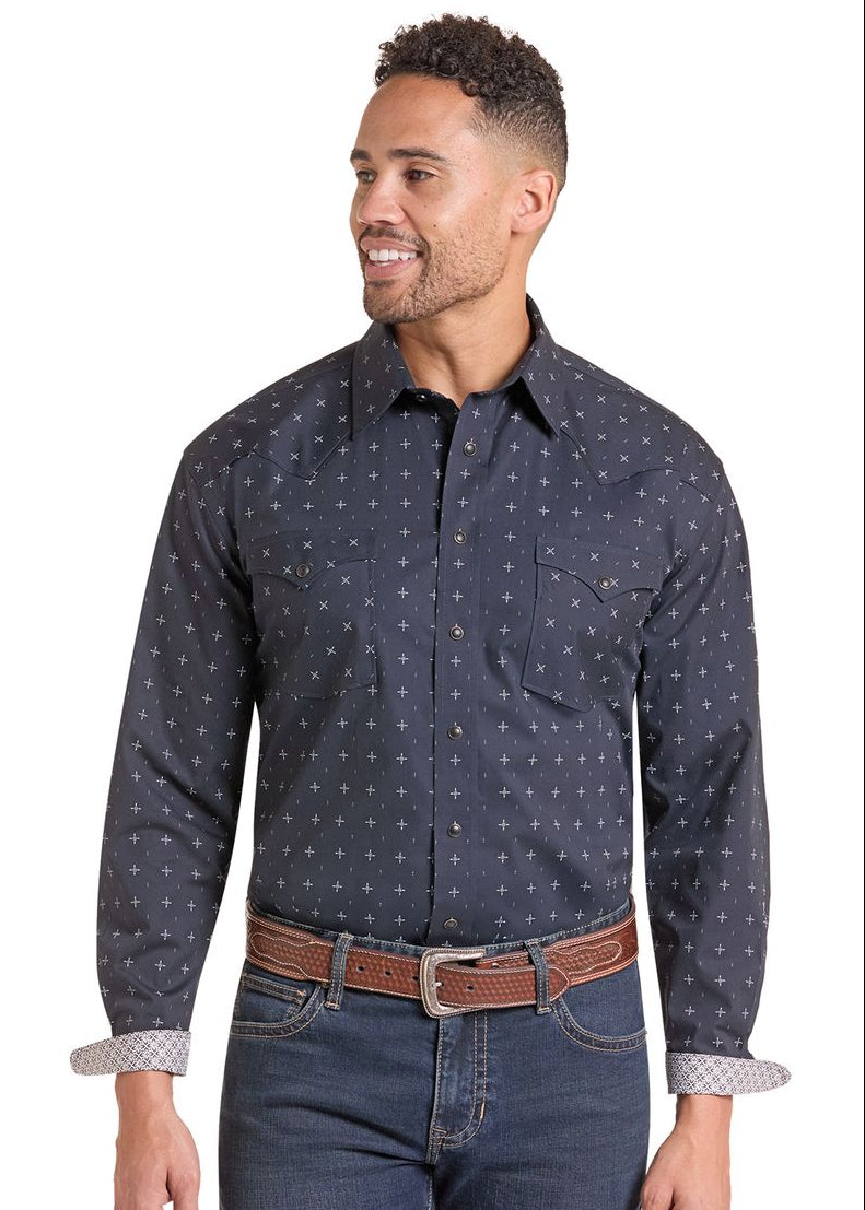A man wearing a dark navy long-sleeve western-style button-down shirt with a small white geometric pattern, paired with blue jeans and a brown belt.